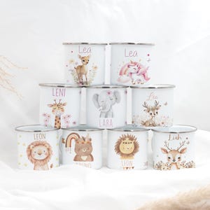 Könnte beinhalten: Satz von neun weißen Emailletassen mit Tierillustrationen und Namen. Die Tassen sind pyramidenförmig gestapelt. Die Tiere umfassen ein Reh, ein Einhorn, eine Giraffe, einen Elefanten, einen Bären, einen Löwen und ein Reh.