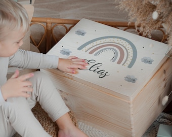 May include: A rectangular light-colored wooden keepsake box featuring a printed design on the lid. The design includes a muted rainbow, the name Elias in black script, and four small gray clouds containing birth data details.