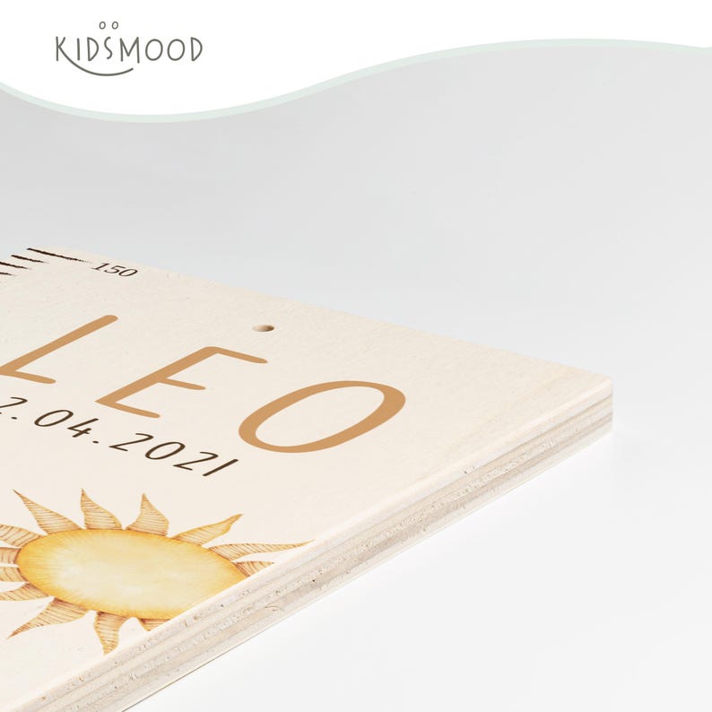 May include: A light-colored wooden growth chart featuring the name LEO in brown letters, the date 07.04.2021, a sun illustration, and measurement markings starting at 150. The brand name KIDSMOOD is printed in the upper left corner.