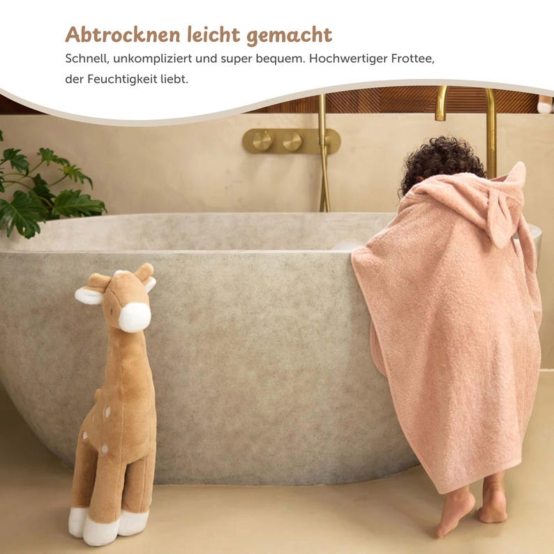 K&ouml;nnte beinhalten: Ein Pl&uuml;sch-Giraffen-Spielzeug und ein rosa Kapuzenhandtuch mit Hasenohren befinden sich in der N&auml;he einer Badewanne. Das Handtuch ist um eine Person gewickelt. Der Text auf dem Bild lautet "Abtrocknen leicht gemacht".