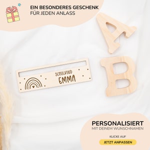 May include: A personalized wooden sign with a rainbow and heart design. The sign says "Schulkind Emma" and is a great gift for a child starting school.