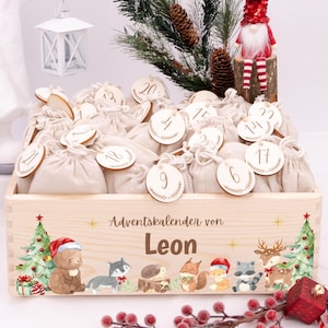 Peut inclure: Un calendrier de l'Avent en bois avec de petits sacs à cordon beiges, chacun numéroté. La boîte est décorée d'illustrations sur le thème de Noël et du nom "Leon". Un petit gnome et un sapin de Noël sont également visibles.
