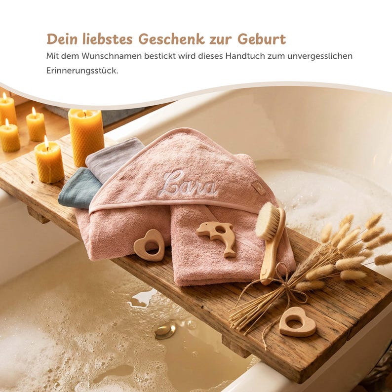 K&ouml;nnte beinhalten: Ein h&ouml;lzernes Badetablett h&auml;lt einen Stapel rosa Kapuzenhandt&uuml;cher mit dem Namen "Cara", zusammen mit einem Holzdelphin, einem herzf&ouml;rmigen Bei&szlig;ring und einer B&uuml;rste. Das Tablett enth&auml;lt auch Trockenblumen und brennende Kerzen.