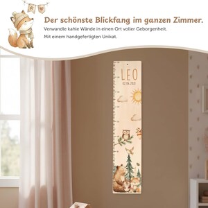 May include: A wooden height chart featuring a printed scale from 50 to 150 cm, the name LEO, and the date 02.04.2021. The design includes watercolor illustrations of a sun, clouds, an owl, a bear, a hedgehog, and a fox among trees.
