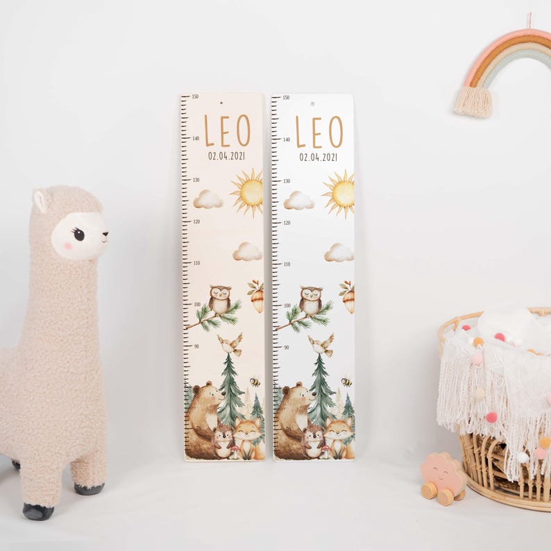 May include: Two vertical wooden growth charts featuring the name LEO and the date 02.04.2021. The charts display a metric scale up to 150 cm, decorated with watercolor illustrations of a sun, clouds, an owl, a bear, and a fox.