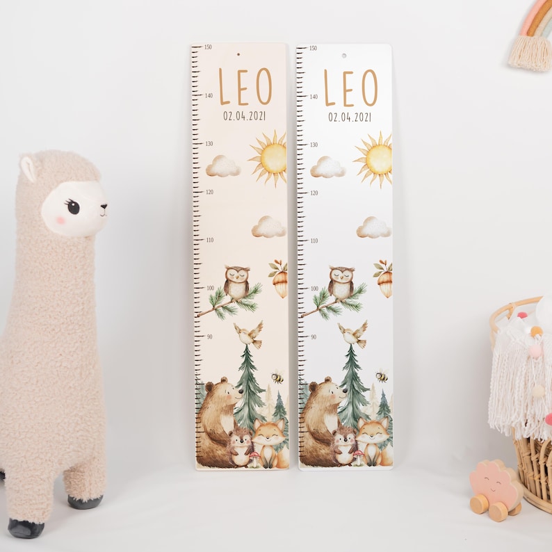 May include: Two vertical wooden growth charts featuring the name LEO and the date 02.04.2021. The charts display a printed forest scene with a bear, fox, owl, sun, clouds, and pine trees, with measurement markings from 80 to 150 cm.