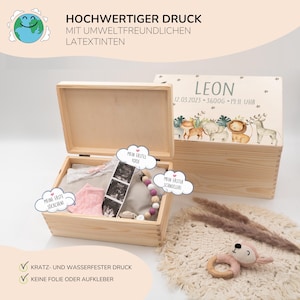 May include: A wooden keepsake box with a light wood finish. The lid is decorated with a colorful illustration of animals and the text "LEON 12.03.2023 - 3600g - 19:11 UHR". The box is open and contains a pink baby sock, a white onesie, a baby rattle, and a sonogram photo. The box is labeled with the text "HOCHWERTIGER DRUCK MIT UMWELTFREUNDLICHEN LATEXTINTEN" and "KRATZ- UND WASSERFESTER DRUCK KEINE FOLIE ODER AUFKLEBER".