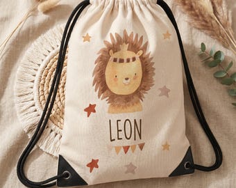 Op de afbeelding: Een beige rugzak met trekkoord met een cartoon leeuwenillustratie met een kroon en de naam "LEON" eronder gedrukt. Het ontwerp bevat sterren en driehoeken in bruin- en oranje tinten. Zwarte trekkoorden en versterkte hoeken maken het ontwerp compleet.