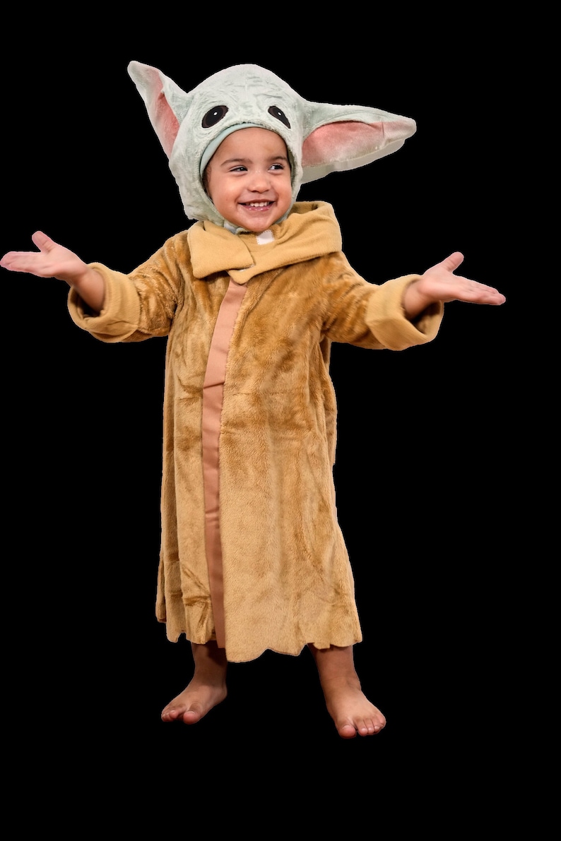 Puede incluir: Un ni&ntilde;o con una bata de color marr&oacute;n peluda y un gorro de color verde y marr&oacute;n peludo con orejas grandes. El ni&ntilde;o sonr&iacute;e y tiene los brazos extendidos.