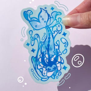 May include: A blue and white sticker featuring a cartoon character with a mermaid tail, surrounded by swirling water and stars. The character is wearing a white dress and has a blue bow on its head.