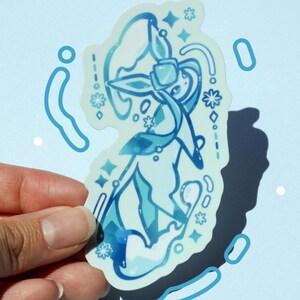 May include: A light blue sticker featuring a stylized illustration of a character with flowing lines and floral accents. The design incorporates various shades of blue and white, with star and droplet details. The sticker is held against a light blue background.