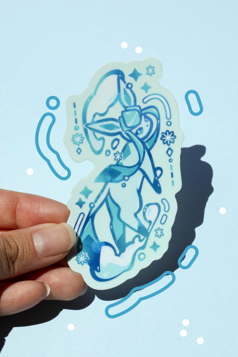 May include: A light blue sticker featuring a stylized illustration of a character with flowing lines and floral accents. The design incorporates various shades of blue and white, with star and droplet details. The sticker is held against a light blue background.