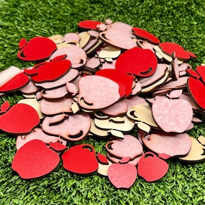 May include: A large collection of small, flat apple-shaped cutouts made of wood. The pieces feature a mix of vibrant red painted surfaces and natural light-colored wood finishes, each with a small stem detail at the top of the apple shape.