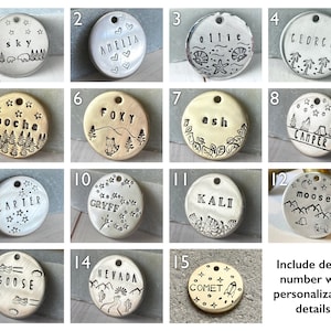 May include: A collection of personalized pet tags with various designs. Each tag is a different shape and features stamped text and illustrations. Designs include names, nature scenes, and celestial motifs. The tags are made of metal.