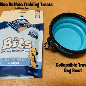 May include: A 9 ounce bag of Blue Buffalo Bits soft-moist training treats for dogs, featuring a tasty chicken recipe. The bag is blue and white with a picture of a dog on it.  Next to the bag is a blue collapsible travel dog bowl.