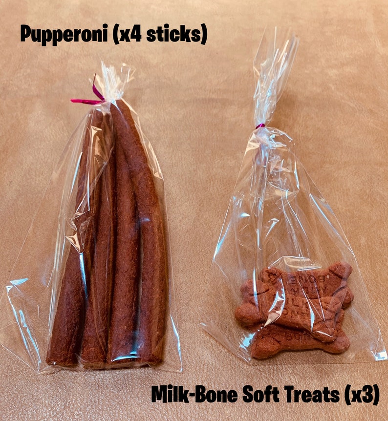 May include: Two bags of dog treats. One bag contains four brown pepperoni sticks. The other bag contains three soft Milk-Bone treats. Both bags are clear plastic.