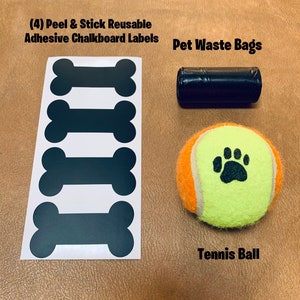 May include: Four black chalkboard bone-shaped labels, a roll of black pet waste bags, and a yellow tennis ball with a black paw print.