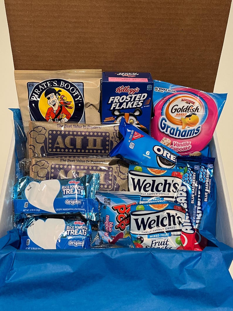 K&ouml;nnte beinhalten: Eine Geschenkbox gef&uuml;llt mit verschiedenen Snacks, darunter Pirate's Booty, Kellogg's Frosted Flakes, Goldfish Grahams, Oreo-Kekse, Rice Krispies Treats und Welch's Fruit Snacks. Die Box ist mit blauem Seidenpapier ausgekleidet.