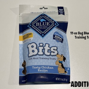 May include: An 11-ounce bag of Blue Buffalo Bits soft-moist training treats for dogs. The bag features a blue and white design with a picture of a dog and the text "Tasty Chicken Recipe".