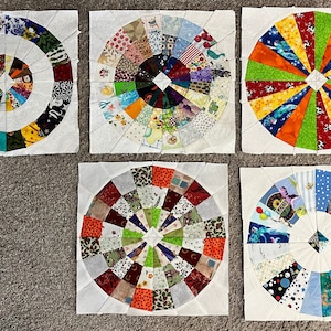 Peut inclure: Six panneaux de tissu carrés avec un fond blanc et un motif circulaire au centre. Chaque panneau présente un motif de patchwork coloré différent avec divers motifs et couleurs, notamment le rouge, le bleu, le vert, le jaune, l'orange et le blanc.