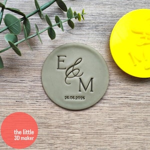 May include: A green round cookie cutter with the letters E & M and the date 25.05.2025.