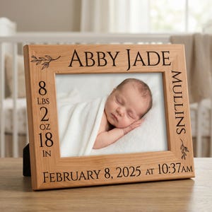 May include: Wooden picture frame with a photo of a sleeping baby. The frame is engraved with the baby's name, birth details, and weight: 8 lbs 2 oz, 18 in. The text reads: "Abby Jade Mullins, February 8, 2025 at 10:37AM."