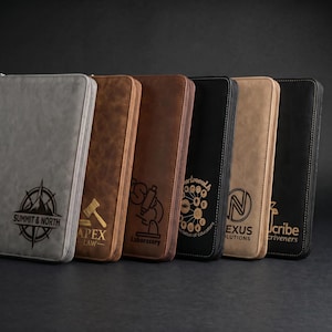 May include: A row of six zippered portfolios in various colors: gray, brown, dark brown, black, tan, and black. Each portfolio features a unique logo and text, including "Summit & North," "Apex Law," and "Laboratory."