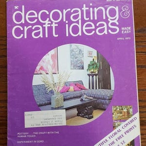 May include: A magazine cover for "Decorating & Craft Ideas" from April 1973. The cover features a photo of a living room with a sectional sofa, a coffee table, and a vase of dried flowers. The text "Beautiful Floral-Covered The Free Prints 57." is visible in the lower right corner.