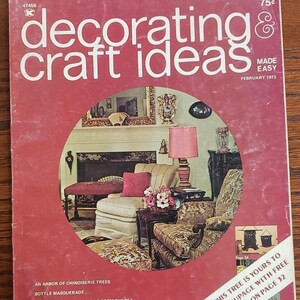 May include: A vintage magazine cover from February 1973 featuring the title "Decorating & Craft Ideas" with the words "Made Easy" printed below. The cover features a photo of a living room with a fireplace, two armchairs, a coffee table, and a lamp with a pink lampshade. The text "This tree is yours to decoupage with free print on page 32" is printed on the bottom right corner of the cover.