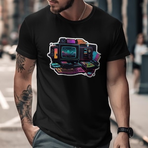 Peut inclure: Un t-shirt noir à manches courtes avec une impression graphique colorée représentant une configuration informatique rétro. Le motif comprend un écran, un clavier et divers appareils électroniques dans des tons vifs de rose, bleu et violet.