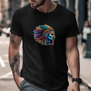 Peut inclure: Un t-shirt noir à manches courtes avec une impression graphique sur la poitrine. Le motif représente le profil d'une personne portant une coiffe à plumes aux couleurs vives, incluant des tons de bleu, orange, jaune, violet et rouge.