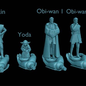 Puede incluir: Figuras impresas en 3D de los personajes de Star Wars Anakin, Yoda y dos versiones de Obi-Wan. Cada figura est&aacute; sobre una base estilizada en forma de mano. Las figuras son de color azul claro sobre un fondo negro.