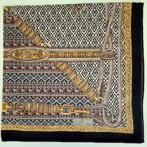 May include: Square silk scarf with a geometric pattern in black, white, and brown. The scarf features ornate gold and brown equestrian-themed designs, including a bridle and rope details. The border is black with a gold trim. The brand name "CELINE" is visible.