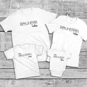 Könnte beinhalten: Vier weiße T-Shirts mit dem Wort "Bauherr" und einem Haus-Symbol bedruckt. Die Shirts sind mit den Namen "Lukas", "Katja", "Leni" und "Ben" personalisiert.