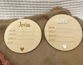 Op de afbeelding: Twee houten baby-aankondigingsplaques met de namen "Jona" en "Leni" erop gegraveerd. Elke plaquette heeft ruimte om de datum, tijd, gewicht en grootte van de baby in te vullen.