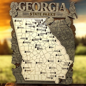May include: A wooden map of Georgia State Parks with the names of each park labeled. The map is surrounded by a decorative border with a bird and flowers.