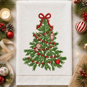 Puede incluir: Un paño de cocina rectangular blanco con un diseño central bordado a máquina de un árbol de Navidad verde. El árbol está decorado con un lazo de cinta roja en la parte superior, una guirnalda de cuentas rojas y varios adornos colgantes.