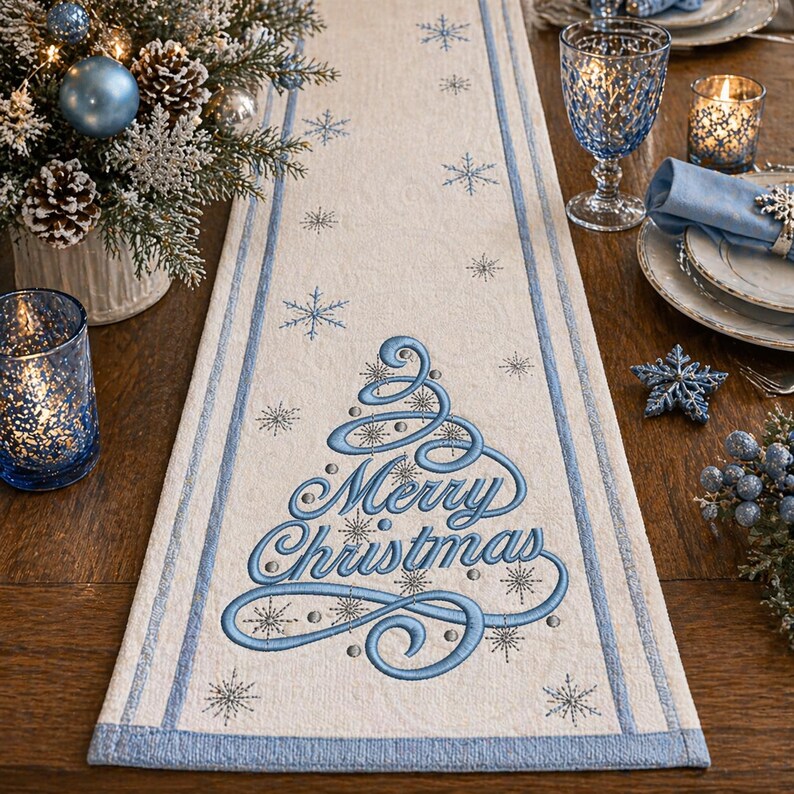 May include: Cream-colored Christmas table runner with a blue border and embroidered Christmas tree design. The words "Merry Christmas" are embroidered in blue. The runner is decorated with snowflakes.