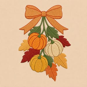 May include: An embroidered design featuring three pumpkins in orange, cream, and yellow, accented with green leaves and autumn-colored foliage in red, gold, and orange, all tied together with a large orange bow at the top of the arrangement.