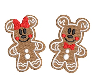 May include: Two embroidered gingerbread cookie designs. One has a red bow, the other a red bow tie. Both have black eyes and smiles, with red cheeks. The cookies are brown with white icing details, resembling a popular cartoon character.
