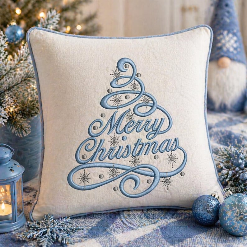 May include: A square, off-white pillow with a light blue embroidered Christmas tree design and the words "Merry Christmas". The pillow has a light blue border and is part of a holiday decor theme.