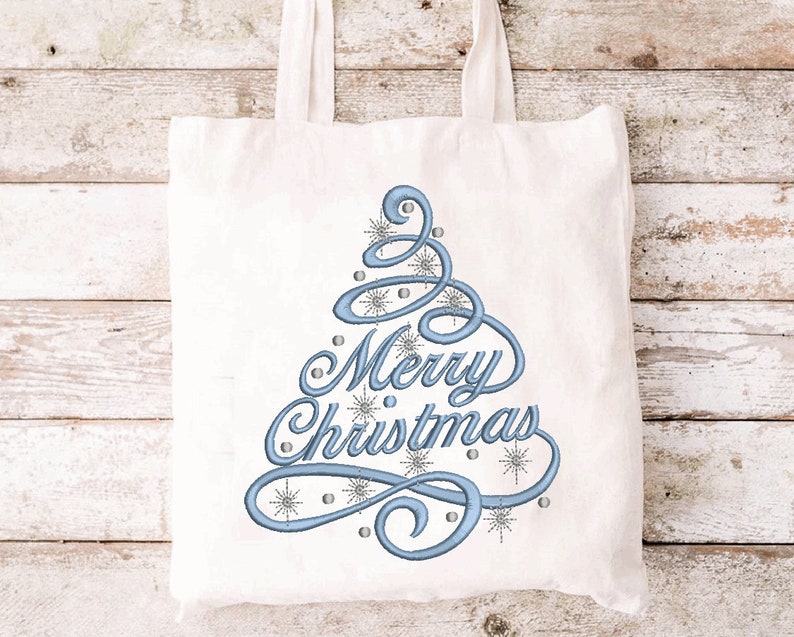 May include: A white tote bag with a blue embroidered Christmas tree design and the words "Merry Christmas". The design includes snowflakes and small silver beads. The bag has two white handles.