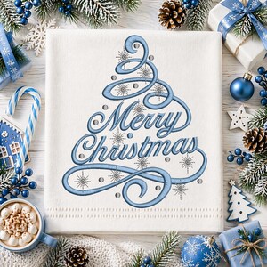 May include: A white Christmas-themed towel with a blue embroidered Christmas tree design and the words "Merry Christmas." The design includes snowflakes and small silver dots. The towel is surrounded by Christmas decorations.