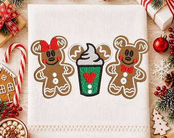 May include: White embroidered towel featuring two gingerbread figures with Mickey Mouse ears and a green cup with a red heart. The gingerbread figures have red bows and bowties. Festive holiday theme.