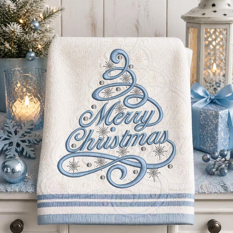 May include: White Christmas-themed towel with a blue embroidered design. The design features a stylized Christmas tree and the words "Merry Christmas" in elegant script. The towel has a blue border.