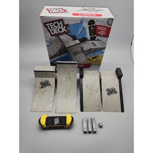 Puede incluir: Un kit de inicio Tech Deck que incluye una caja de cartón con gráficos de rampas de skate, un fingerboard con protectores laterales amarillos, cuatro rampas grises con bordes negros y tres conectores metálicos plateados.