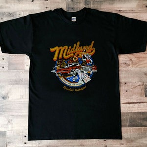 Może przedstawiać: Czarny T-shirt z kolorowym wzorem graficznym przedstawiającym słowo "Midland" w retro czcionce, karikaturę kobiety w kowbojskim kapeluszu, czerwony samochód i tekst "People say I've got a Drinkin' Problem".