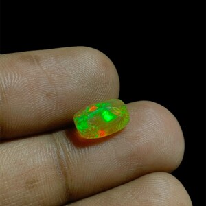 May include: A green, yellow, and red opal gemstone with a rectangular shape.