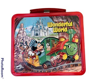 May include: Red metal lunchbox featuring a vintage illustration of Mickey Mouse, Pluto, and Donald Duck riding a train through a depiction of Walt Disney World. The lunchbox has the text "Walt Disney's Wonderful World" on the front.