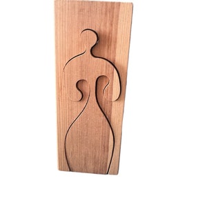 May include: A wooden cutout of a person's silhouette, with a simple design, is mounted on a wooden board.